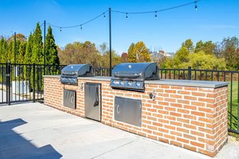 A brick wall with two grills on top and a black fence behind it.
